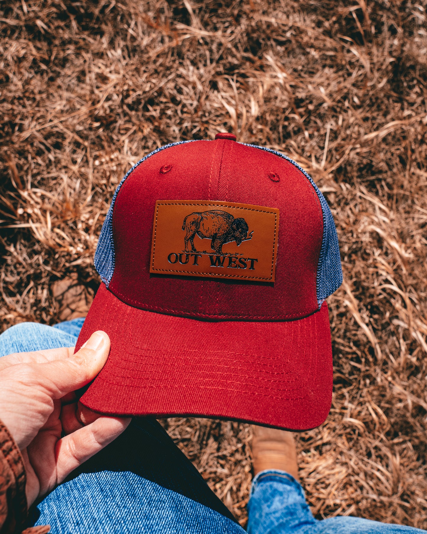 Out West ball cap in Burgundy-  Our in-demand trucker caps are finally here + proudly designed by Out West! Not only fun & functional but truly a stylish staple piece for any rancher!  A gorgeous burgundy color with a navy mesh back & adjustable strap.  A unique twist to this cap; the underside of the peak has a western-style pattern!