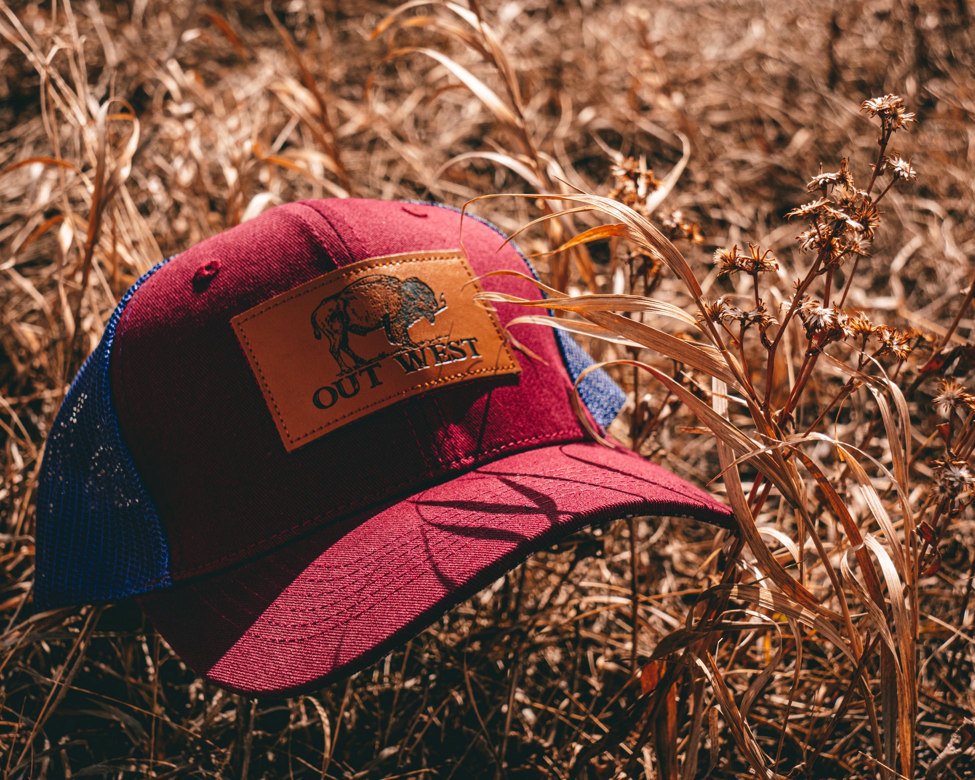 Out West ball cap in Burgundy-  Our in-demand trucker caps are finally here + proudly designed by Out West! Not only fun & functional but truly a stylish staple piece for any rancher!  A gorgeous burgundy color with a navy mesh back & adjustable strap.  A unique twist to this cap; the underside of the peak has a western-style pattern!