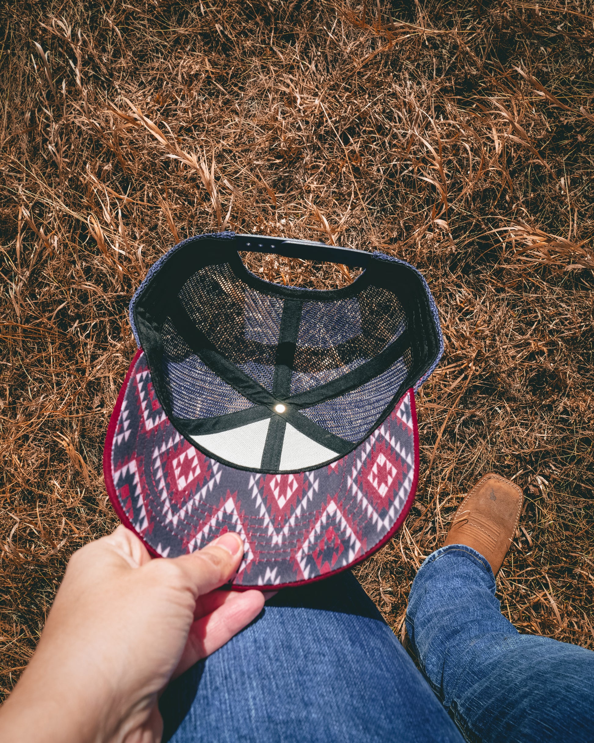 Out West ball cap in Burgundy-  Our in-demand trucker caps are finally here + proudly designed by Out West! Not only fun & functional but truly a stylish staple piece for any rancher!  A gorgeous burgundy color with a navy mesh back & adjustable strap.  A unique twist to this cap; the underside of the peak has a western-style pattern!