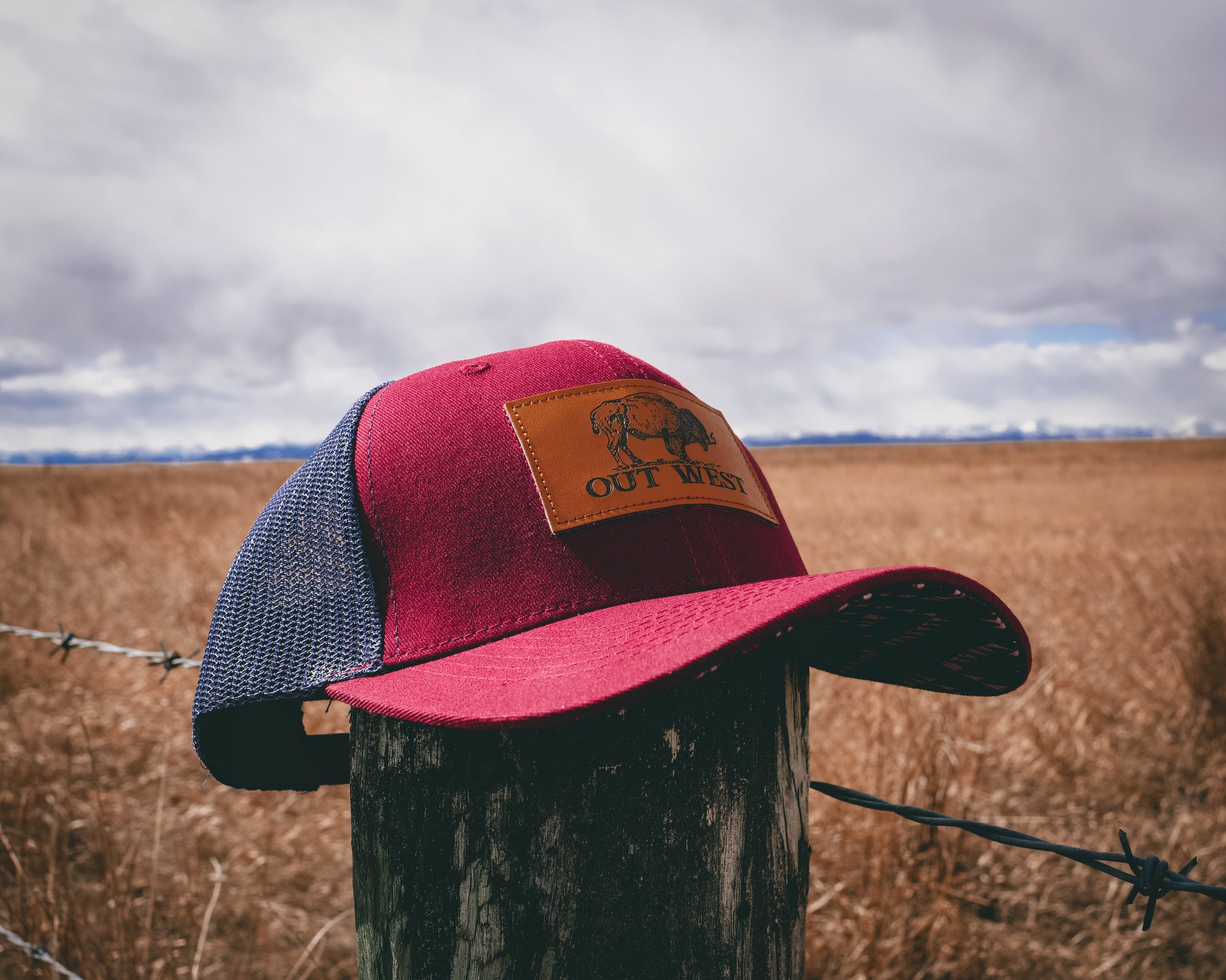 Out West ball cap in Burgundy-  Our in-demand trucker caps are finally here + proudly designed by Out West! Not only fun & functional but truly a stylish staple piece for any rancher!  A gorgeous burgundy color with a navy mesh back & adjustable strap.  A unique twist to this cap; the underside of the peak has a western-style pattern!