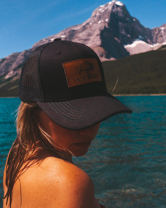 Out West ball cap in Black-  Our in-demand trucker caps are finally here + proudly designed by Out West! Not only fun & functional but truly a stylish staple piece for any rancher!  Black with black mesh back & adjustable strap. The underside of the peak is burgundy with a dark green trim.